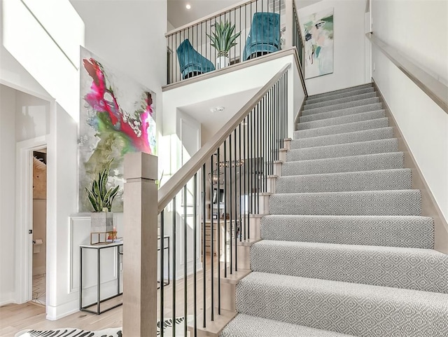 stairs with hardwood / wood-style floors and a high ceiling