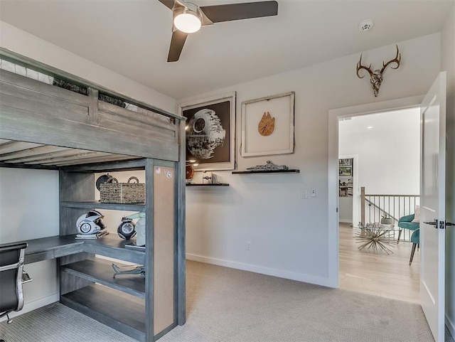 carpeted home office with ceiling fan and built in desk