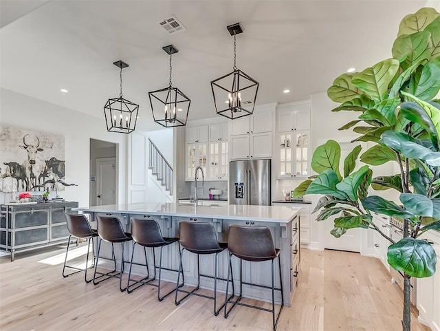 kitchen featuring stainless steel fridge, pendant lighting, white cabinetry, and a spacious island