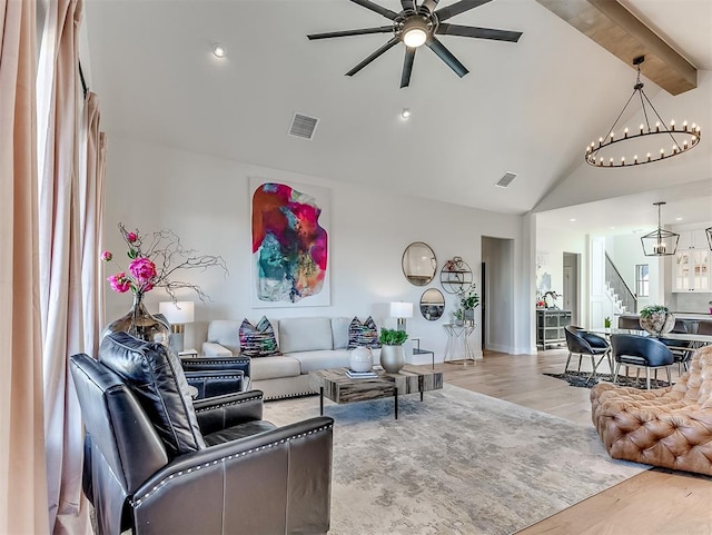 living room featuring beam ceiling, high vaulted ceiling, ceiling fan with notable chandelier, and light wood-type flooring