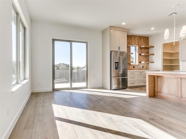 kitchen with pendant lighting, high quality fridge, light hardwood / wood-style flooring, and a healthy amount of sunlight