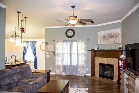 living room featuring a tile fireplace, dark hardwood / wood-style flooring, ceiling fan, and ornamental molding