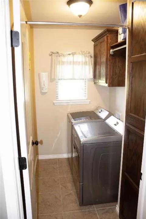 laundry room with cabinets, washing machine and dryer, and light tile patterned floors