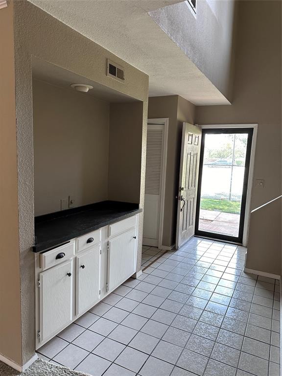 kitchen with a textured ceiling, white cabinets, and light tile patterned floors