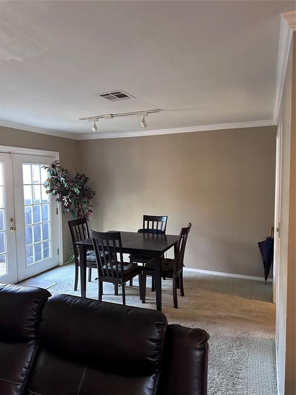 dining room featuring light carpet, french doors, crown molding, and track lighting