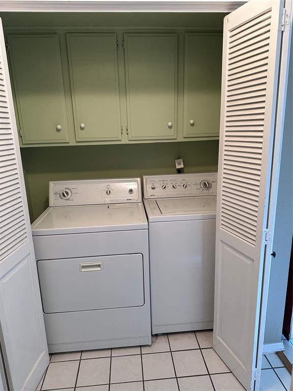 laundry area with light tile patterned flooring, cabinets, and separate washer and dryer