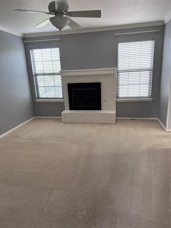 unfurnished living room with carpet flooring, a brick fireplace, ceiling fan, and crown molding