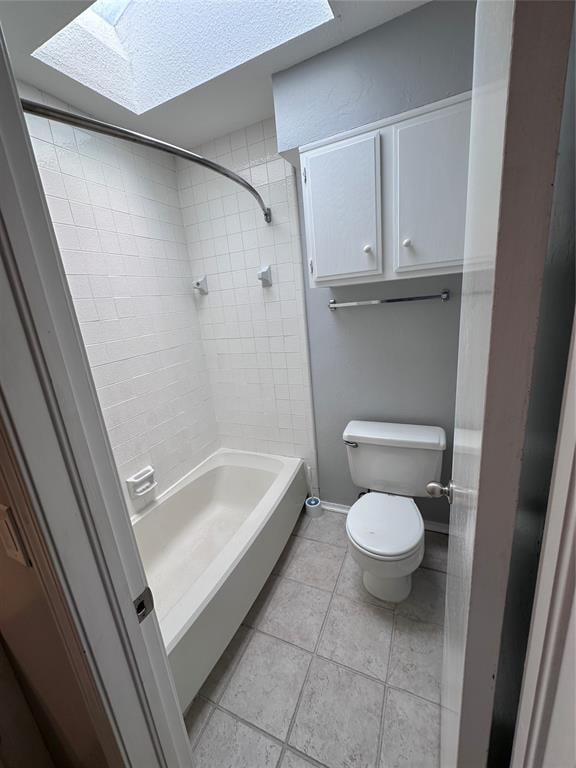 bathroom with tile patterned flooring, tiled shower / bath combo, toilet, and a skylight