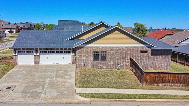 craftsman-style house with fence, an attached garage, brick siding, a front yard, and concrete driveway