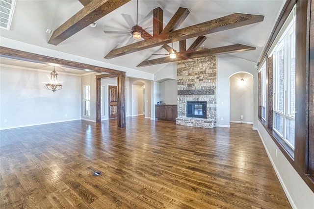 unfurnished living room featuring arched walkways, beamed ceiling, ceiling fan with notable chandelier, and a fireplace