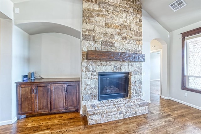 living area with visible vents, plenty of natural light, wood finished floors, and lofted ceiling