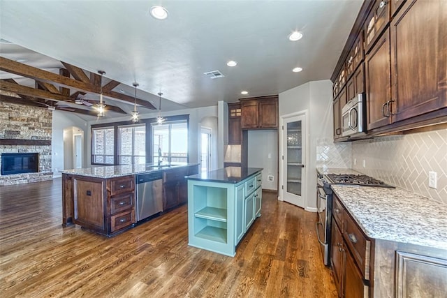 kitchen with open shelves, appliances with stainless steel finishes, a center island, open floor plan, and visible vents