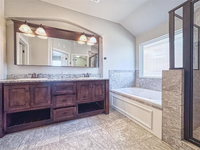 bathroom featuring double vanity, vaulted ceiling, a sink, and a garden tub