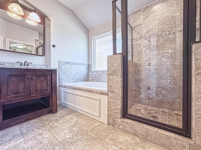 bathroom with vaulted ceiling, vanity, a shower stall, and a garden tub
