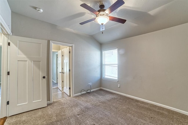 unfurnished bedroom featuring baseboards, a ceiling fan, carpet, and lofted ceiling