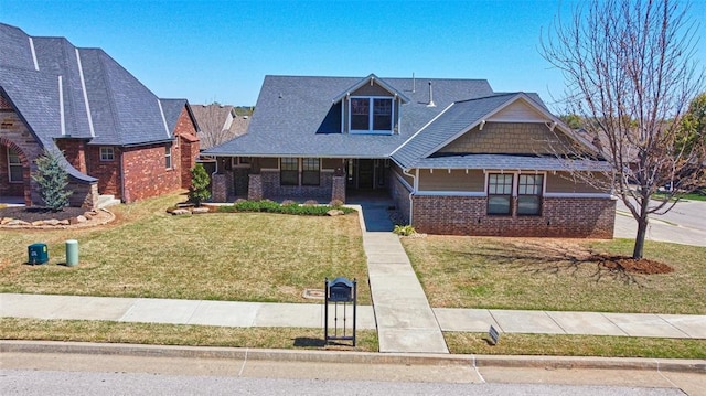 craftsman inspired home with a porch, a front lawn, and brick siding