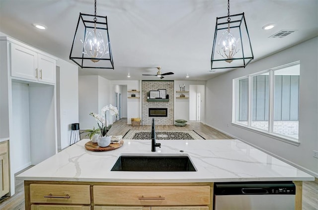 kitchen with light stone countertops, sink, a center island, and stainless steel dishwasher