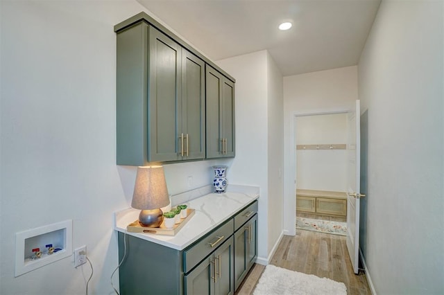 interior space with cabinets, hookup for a washing machine, and light hardwood / wood-style floors