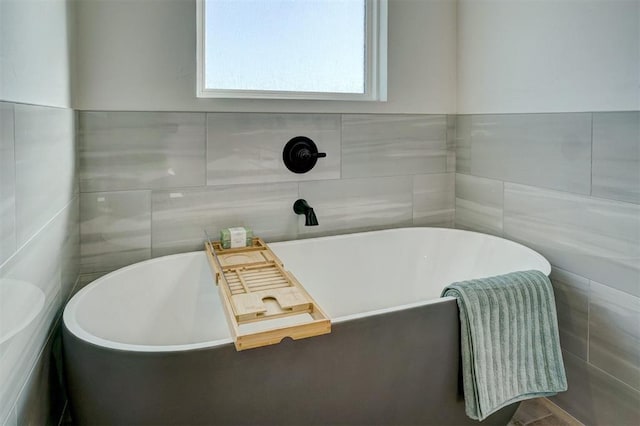 bathroom featuring tile walls and a tub to relax in