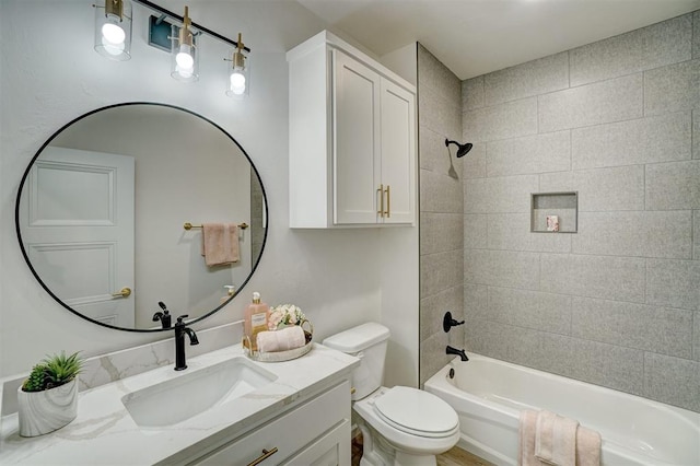 full bathroom featuring tiled shower / bath, vanity, and toilet