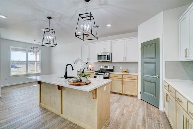 kitchen with light stone countertops, appliances with stainless steel finishes, sink, and a center island with sink