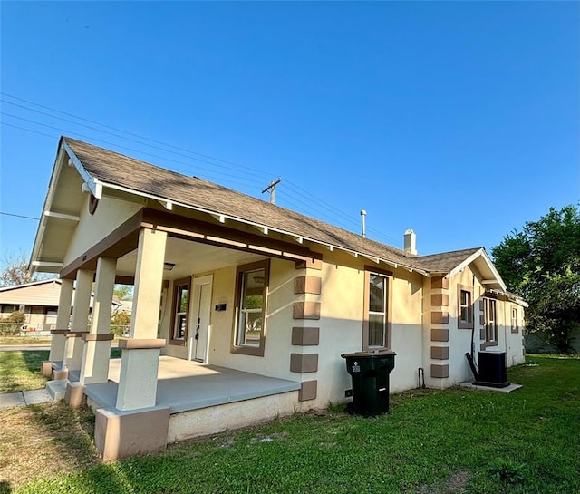 back of house featuring cooling unit, covered porch, and a yard