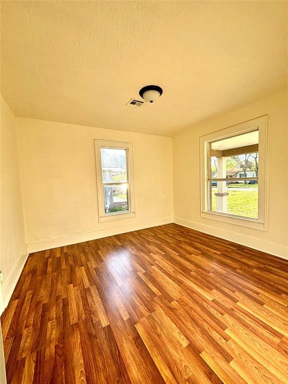 spare room with a healthy amount of sunlight, wood-type flooring, and a textured ceiling