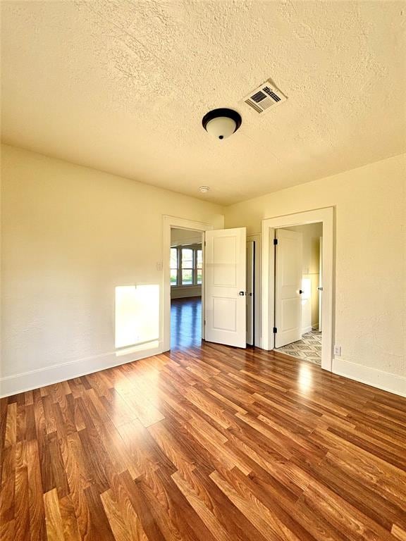 unfurnished room featuring wood-type flooring and a textured ceiling