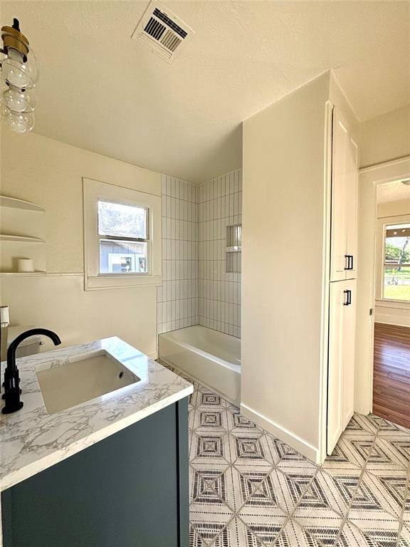 bathroom featuring vanity, wood-type flooring, and tiled shower / bath