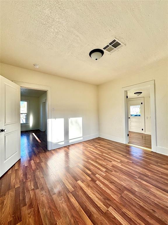 unfurnished room featuring dark hardwood / wood-style flooring and a textured ceiling