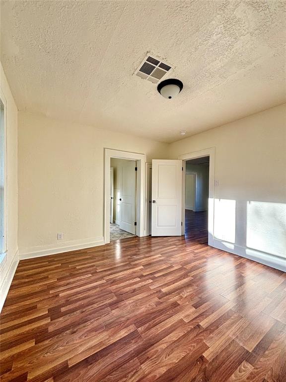 unfurnished room featuring wood-type flooring and a textured ceiling