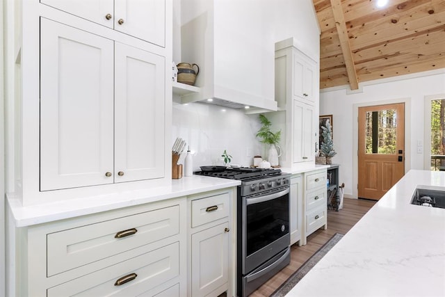 kitchen with stainless steel range with gas cooktop, wood-type flooring, wooden ceiling, vaulted ceiling with beams, and white cabinetry