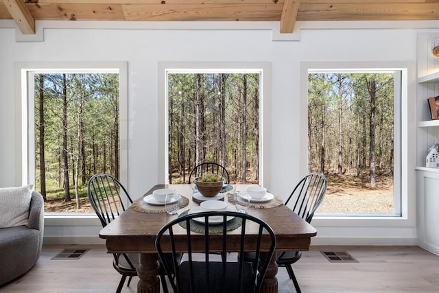 dining area with beamed ceiling, light wood-type flooring, and a healthy amount of sunlight