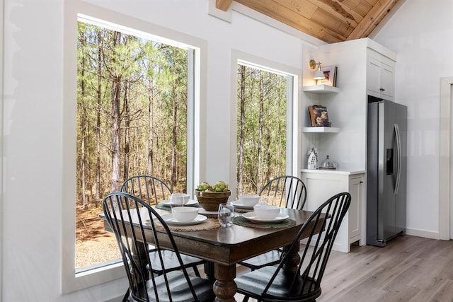 dining area with vaulted ceiling, light hardwood / wood-style flooring, a wealth of natural light, and wooden ceiling