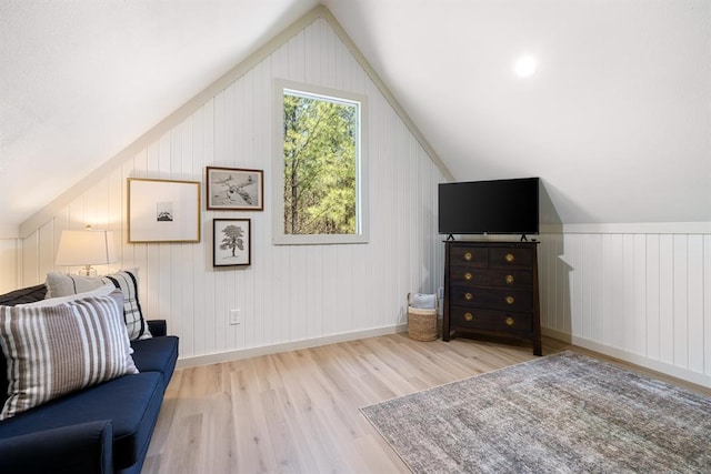 living area with vaulted ceiling, light hardwood / wood-style flooring, and wooden walls