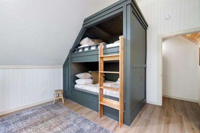 bedroom featuring lofted ceiling, wood walls, and wood-type flooring