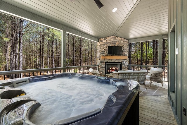 wooden terrace featuring a hot tub and an outdoor stone fireplace