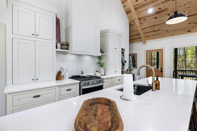 kitchen featuring gas stove, light stone countertops, sink, and decorative light fixtures