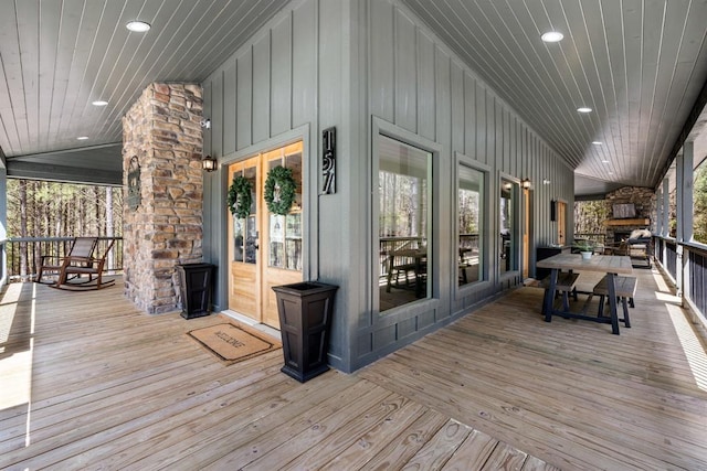 wooden terrace featuring an outdoor stone fireplace and french doors