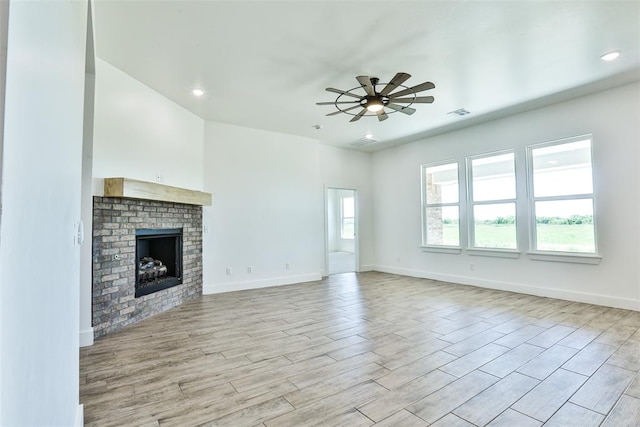 unfurnished living room with ceiling fan, a fireplace, and light hardwood / wood-style flooring