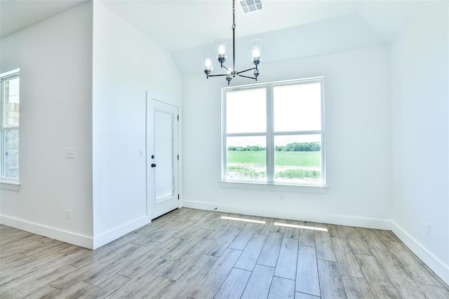 unfurnished room featuring light wood-type flooring, an inviting chandelier, and lofted ceiling