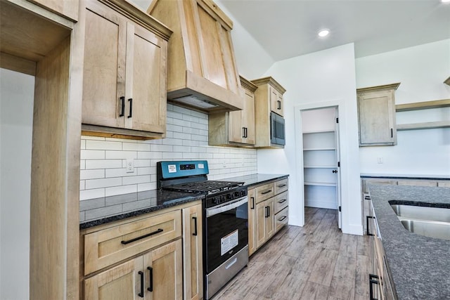 kitchen with light brown cabinetry, stainless steel appliances, light hardwood / wood-style floors, and custom exhaust hood