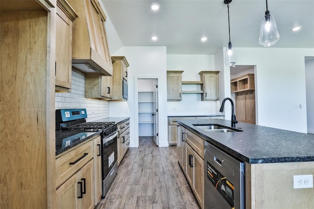 kitchen with appliances with stainless steel finishes, sink, decorative light fixtures, a center island with sink, and light hardwood / wood-style floors