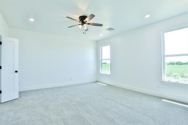 spare room featuring a wealth of natural light, ceiling fan, and light colored carpet