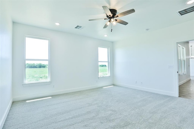 spare room with light carpet, plenty of natural light, and ceiling fan