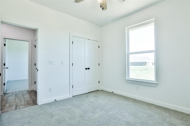 unfurnished bedroom featuring a closet, light colored carpet, and ceiling fan