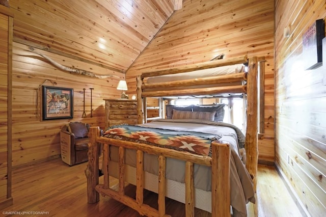 bedroom featuring light hardwood / wood-style floors, vaulted ceiling, wooden ceiling, and wood walls