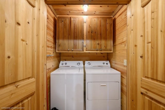 laundry area featuring wooden walls, cabinets, and independent washer and dryer