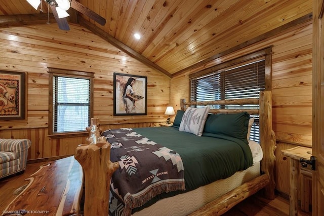 bedroom with wood ceiling, lofted ceiling with skylight, ceiling fan, wooden walls, and hardwood / wood-style floors