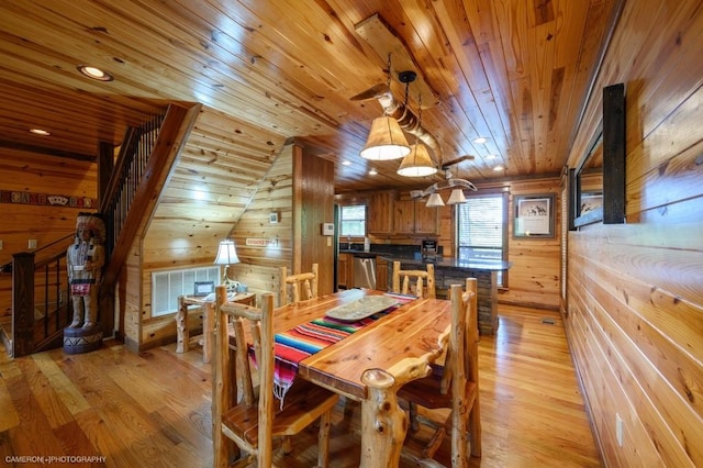 dining space with lofted ceiling, light hardwood / wood-style flooring, wooden walls, and wood ceiling